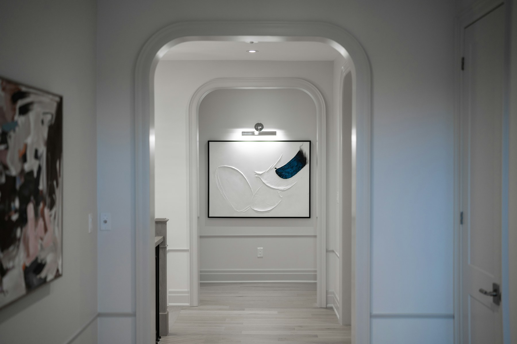 A refined hallway with softly rounded archways and abstract artwork